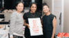 Three young women holding risograph posters