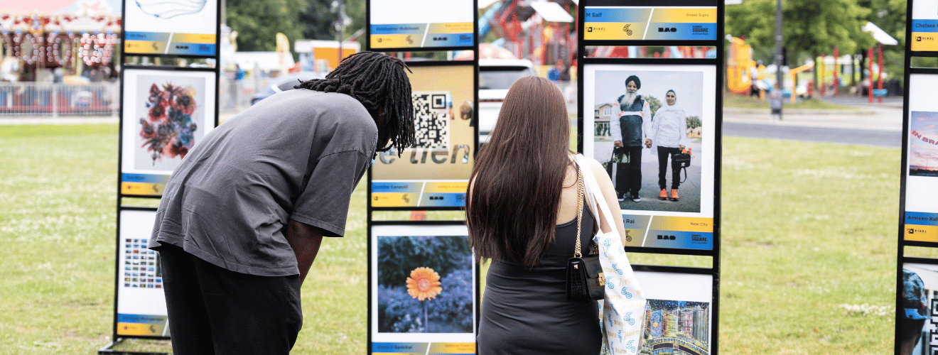 Photograph of a man and woman looking at the PIXEL: Chapter 50 Digital Art Exhibition at the City of Brampton's 50th Birthday