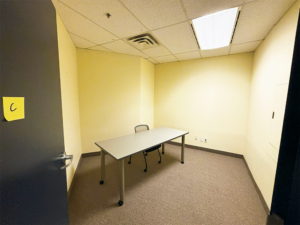 Photograph of Studio C in the BAO office. A small windowless room with a table and chair in it