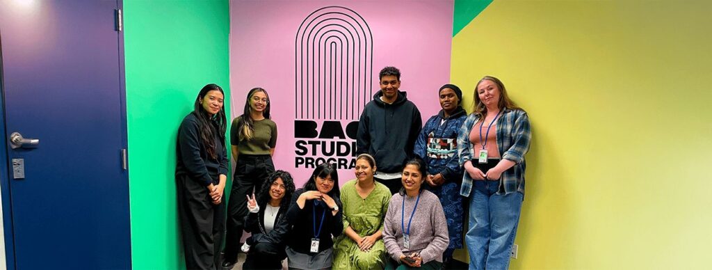 A group of artists taking a photo in front of a colourful wall
