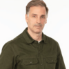 White man with short brown and grayish hair. He is wearing a dark green button-up shirt with a white t-shirt underneath.