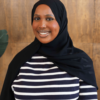 Young Black woman who is wearing a black hijab and a black and white stripped long sleeved blouse