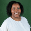 Photograph of Shiemara Hogarth, a Black woman with curly black hair wearing a white blouse against a solid green background.